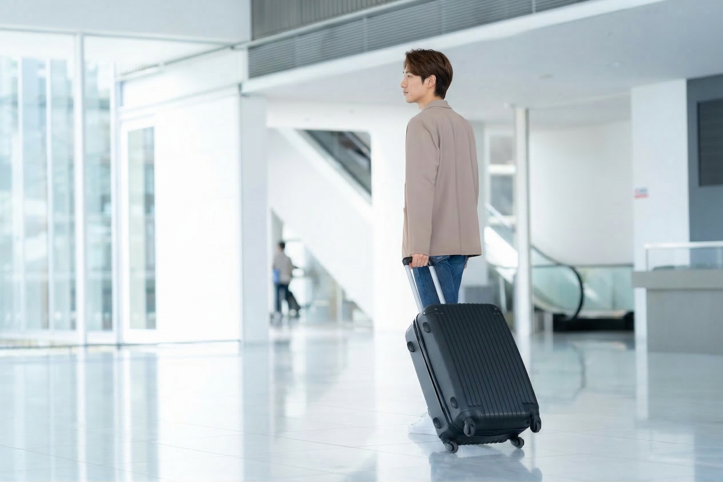 空港でスーツケースを引くビジネスマン