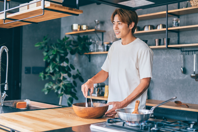 スタイリッシュなキッチンで料理する男性のイラスト