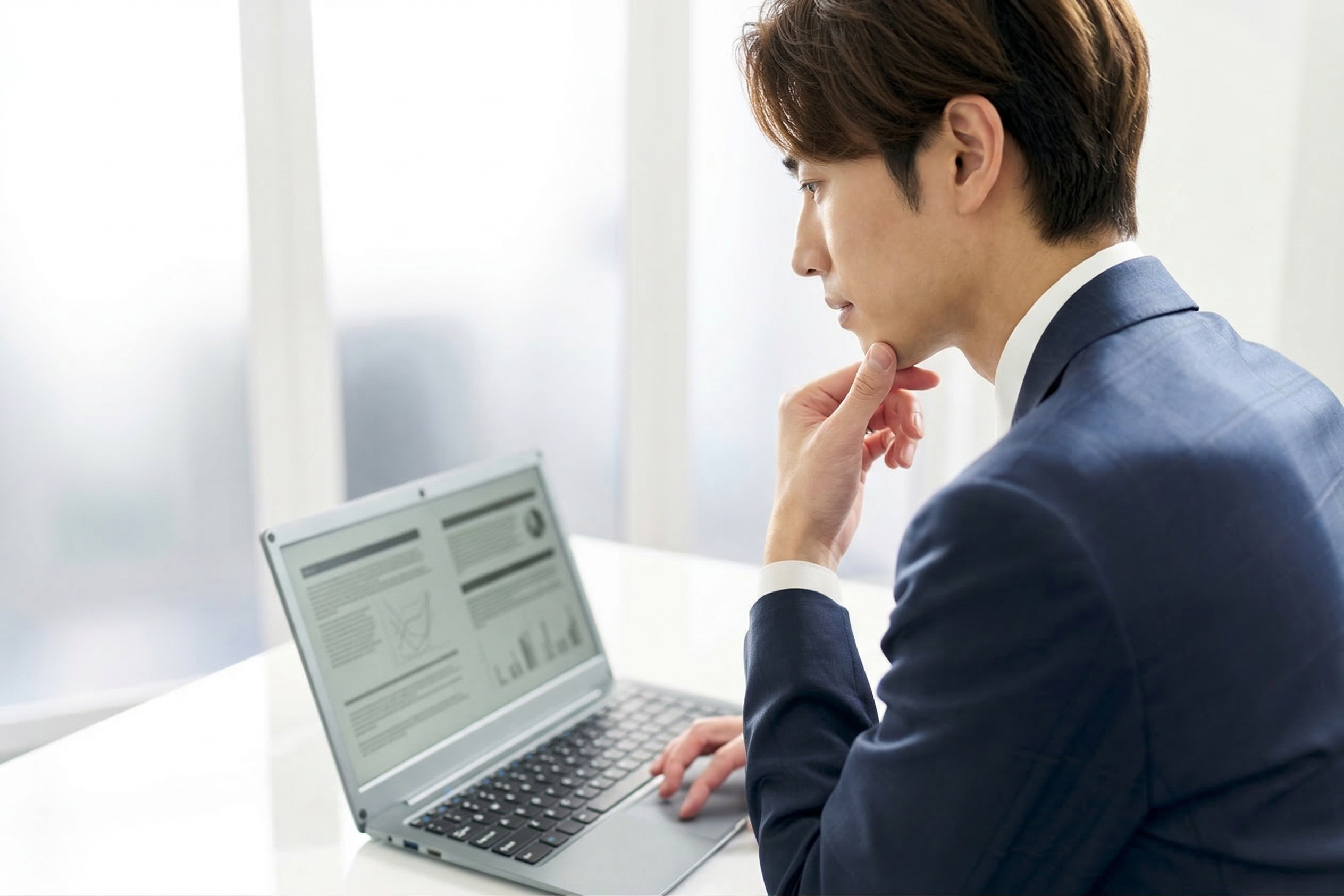 ノートPCを見ながら考え込む男性の横顔