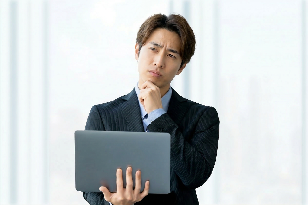 ノートPCを見て悩む男性