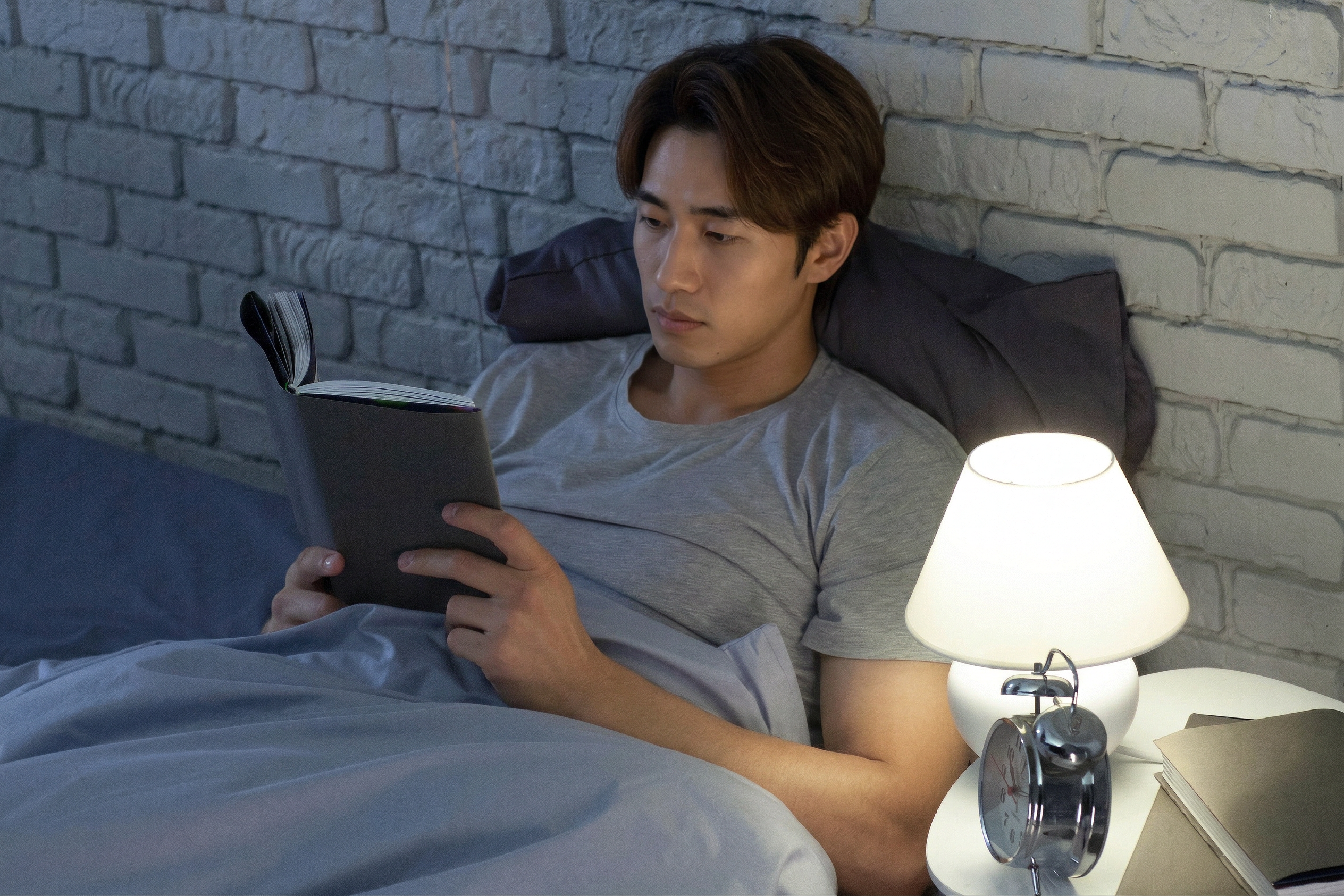 ベッドで本を読む男性