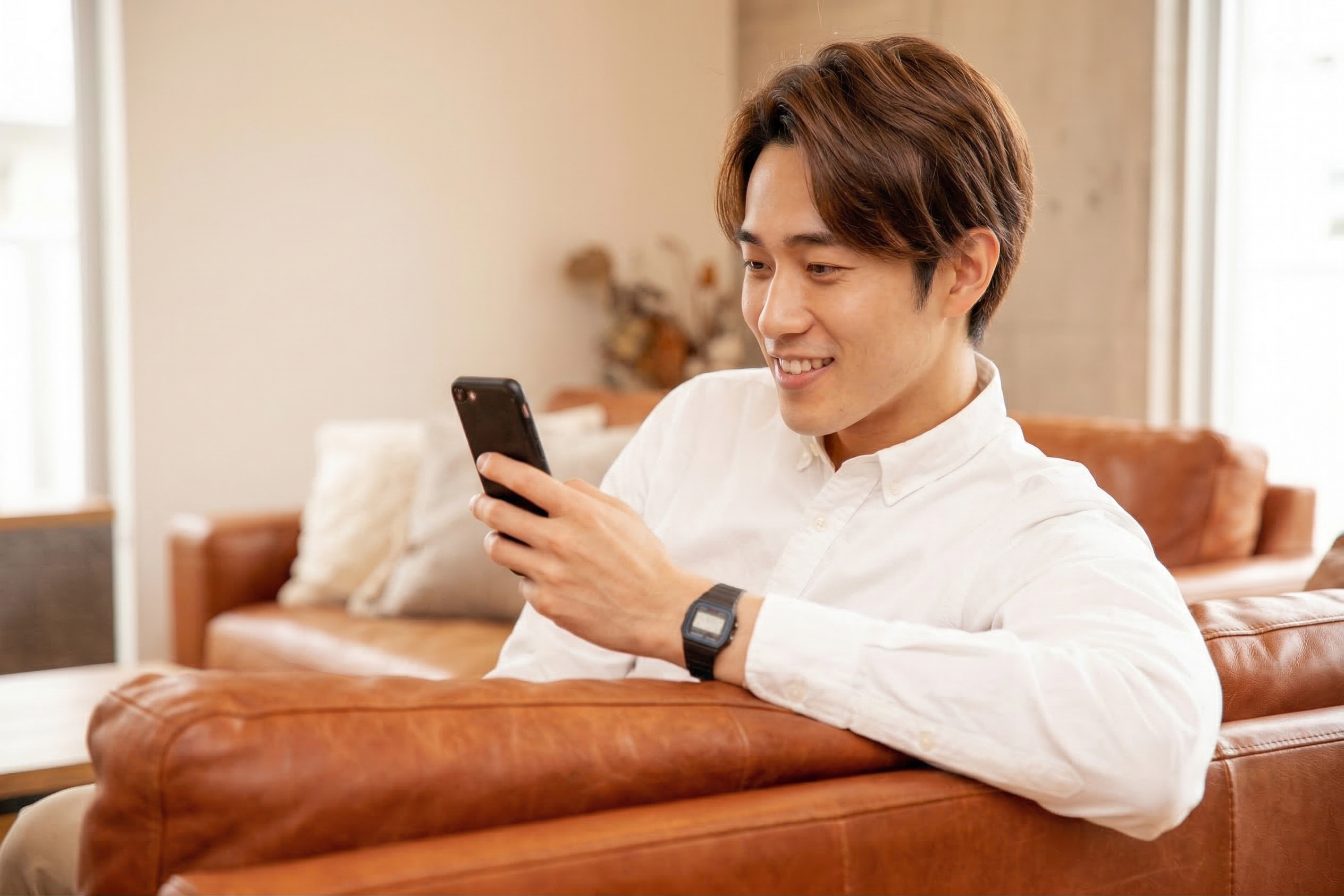 夜にソファでリラックスしてPCを操作する男性