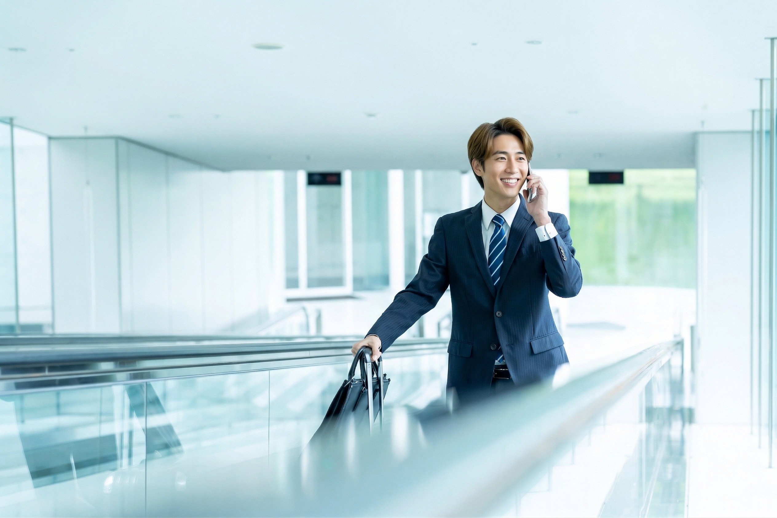 動く歩道でスマホを確認するビジネスマン